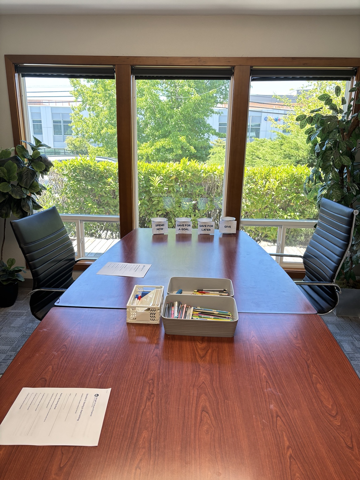 A sunny classroom prepared with pencils, worksheets, and four labeled saving and spending containers