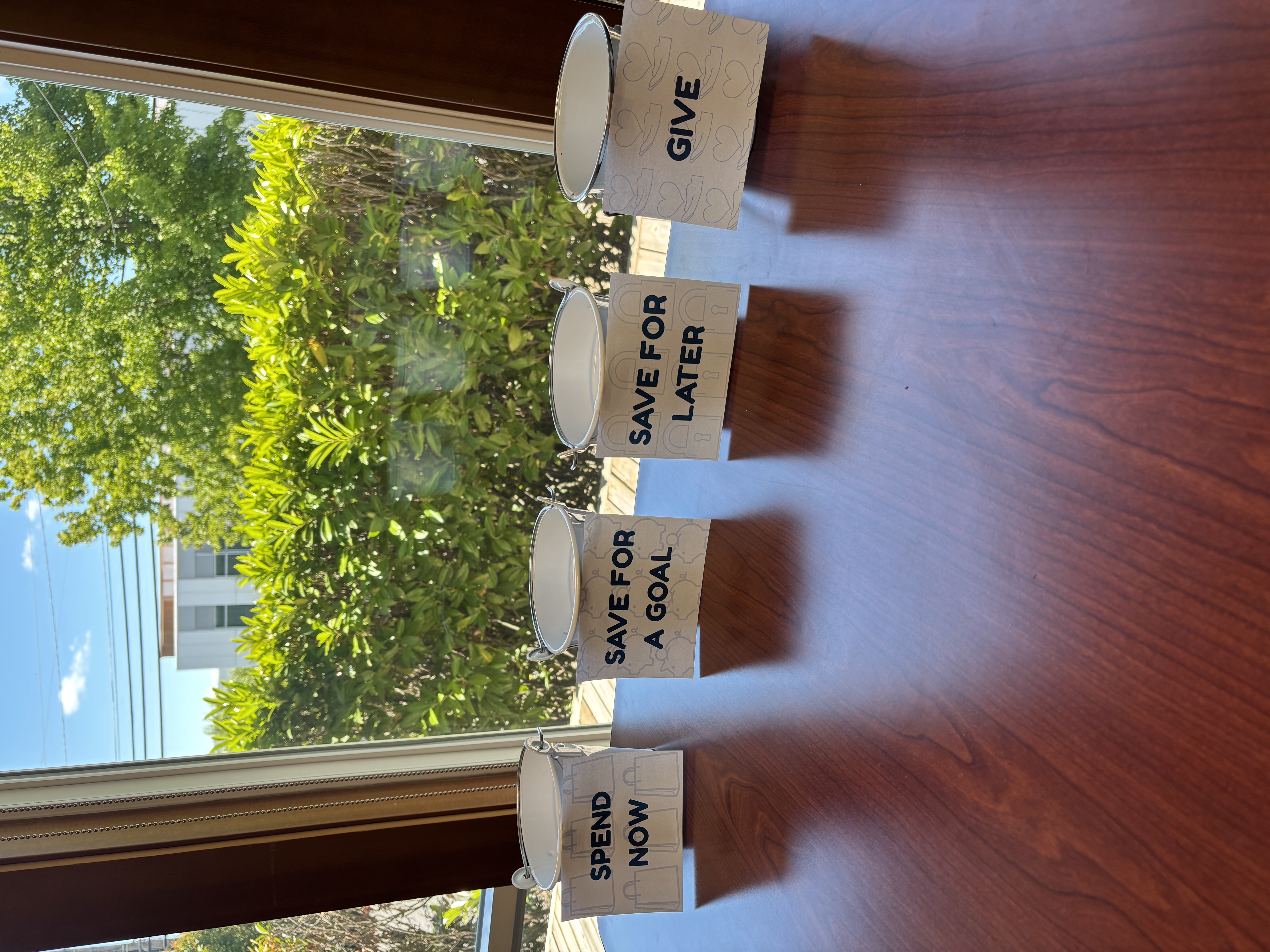 Four labeled jars for spending now, saving for a goal, saving for later, and giving